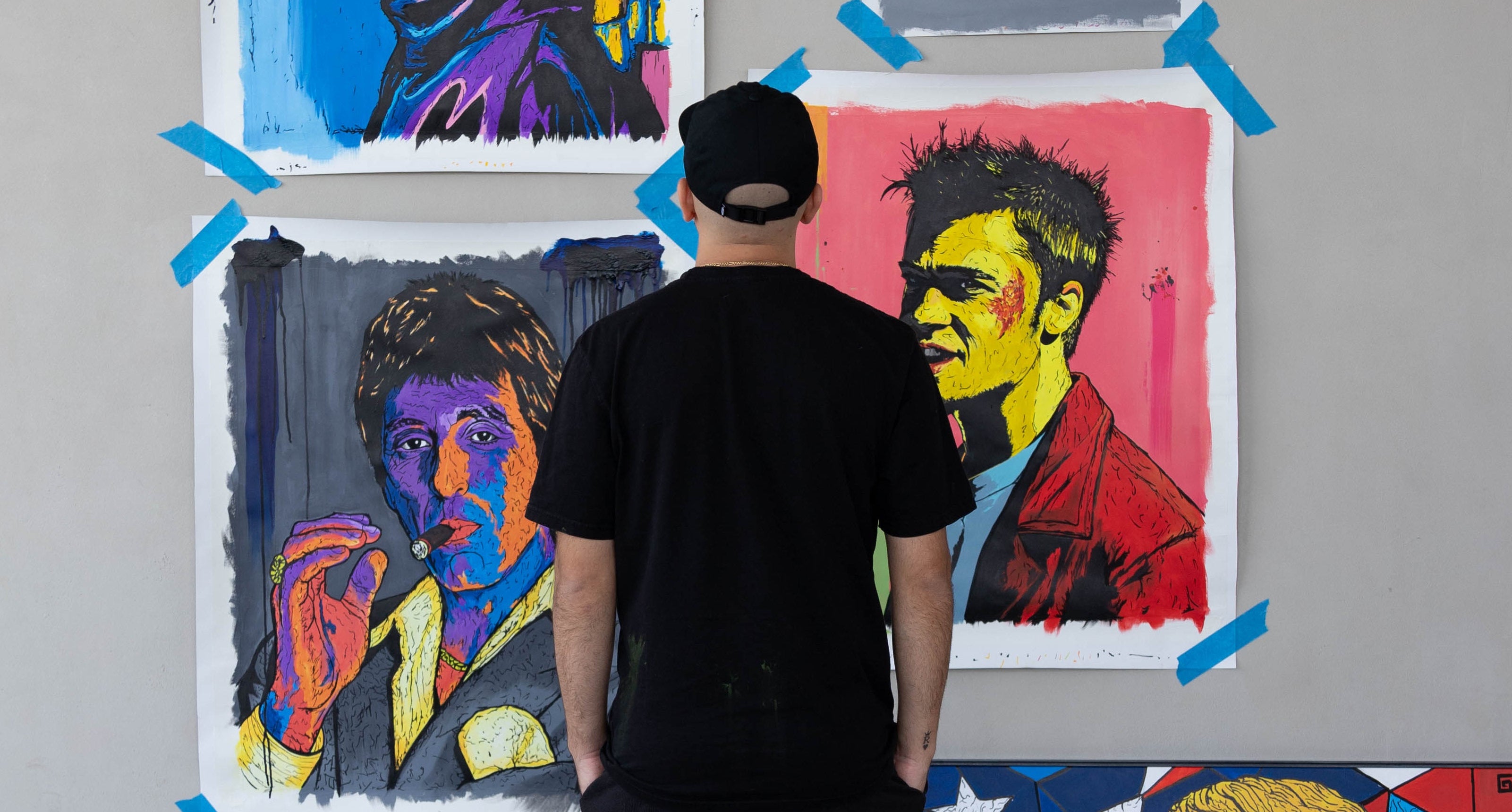 Person standing in front of a wall with colorful artworks.